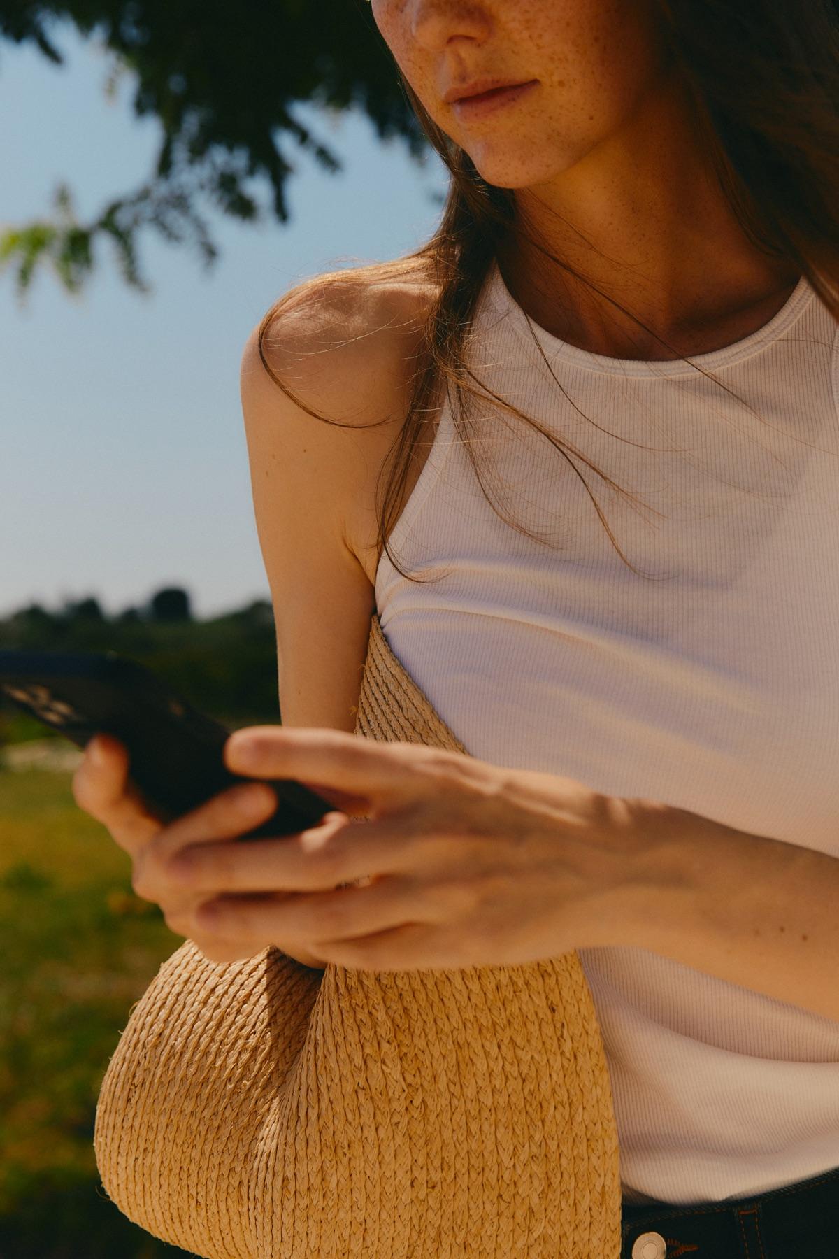 A woman outdoors typing a message on her phone