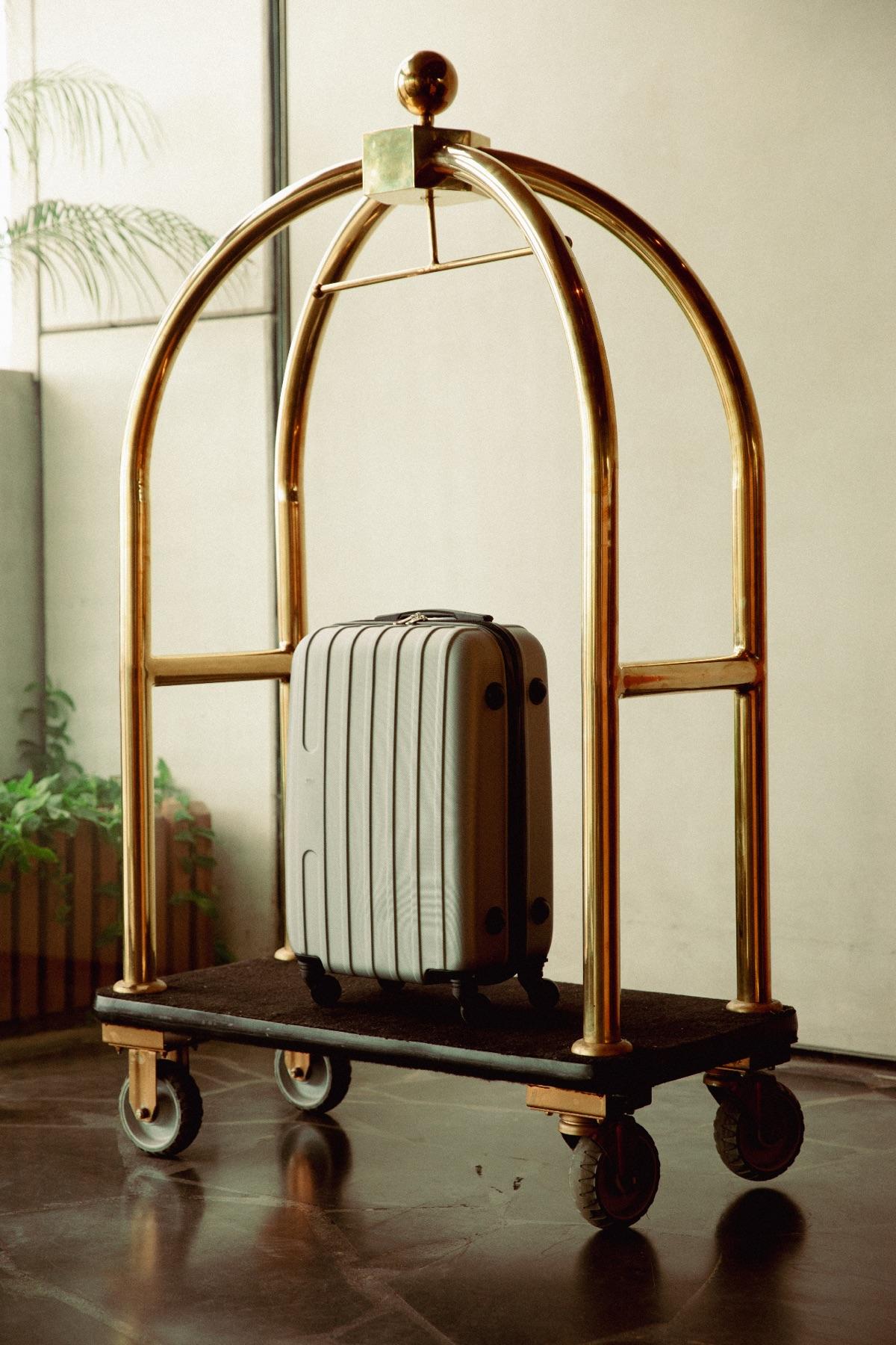 A suitcase on a brass hotel luggage cart