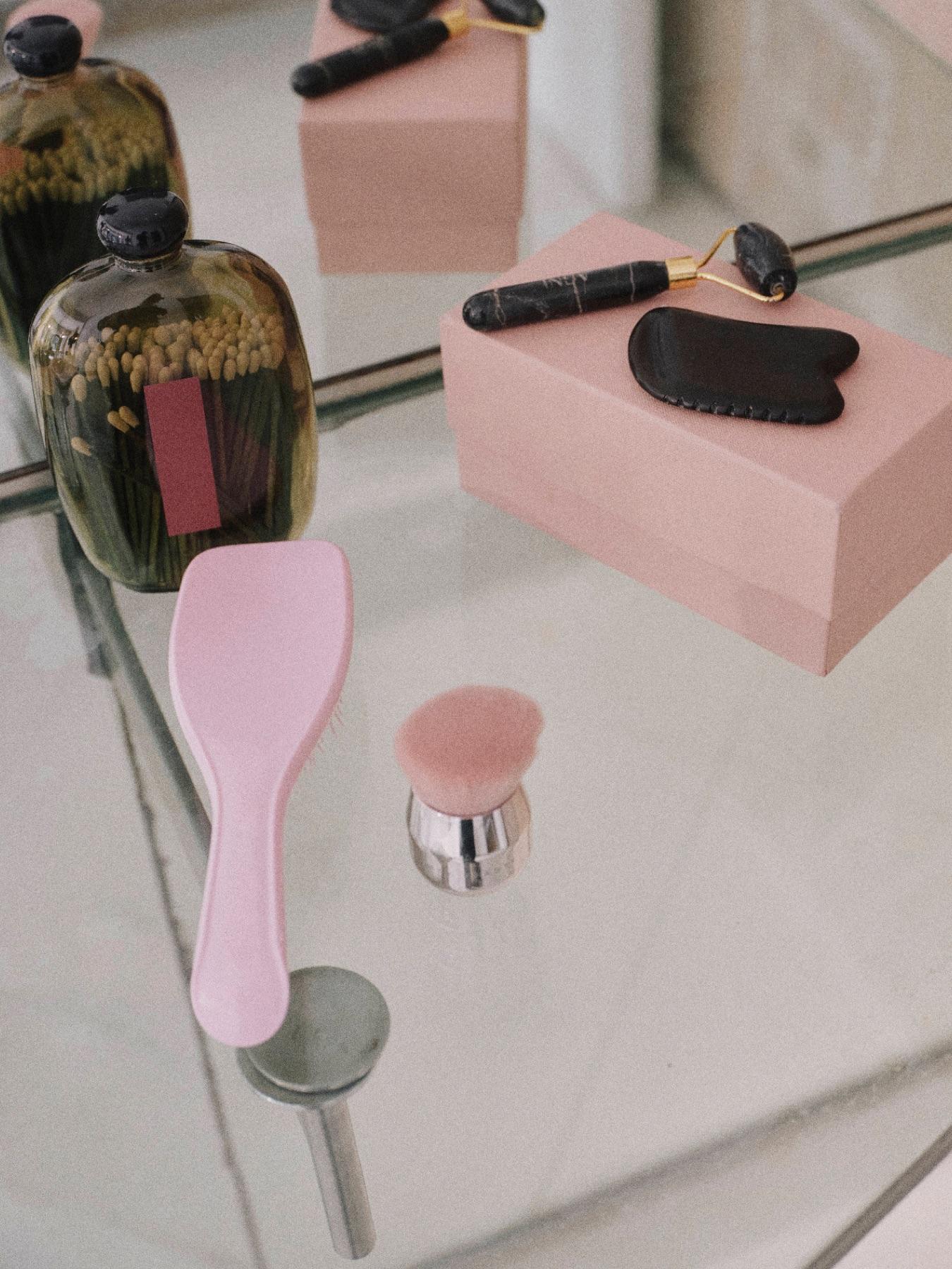 Beauty products and a pink box arranged on a glass table