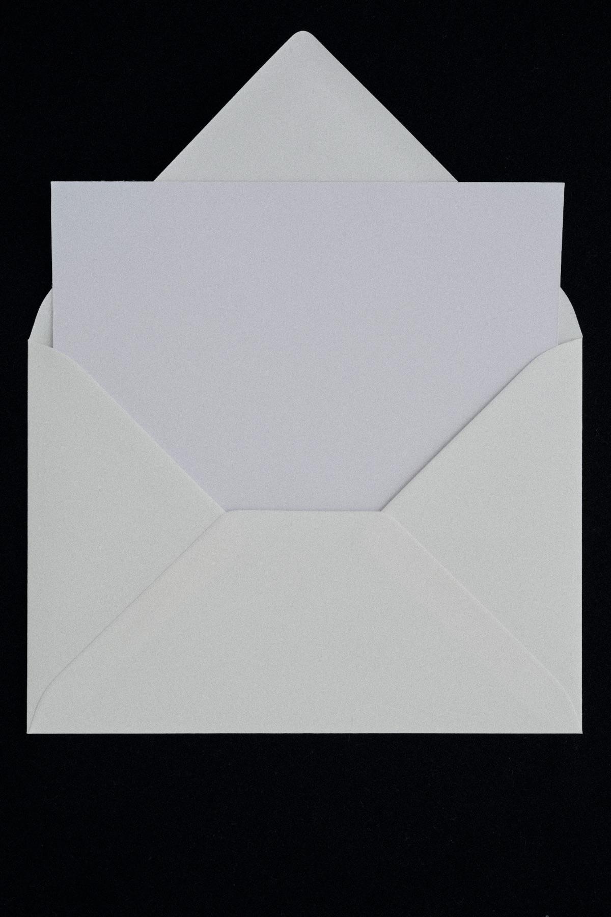 An open white envelope with a blank card on a black background