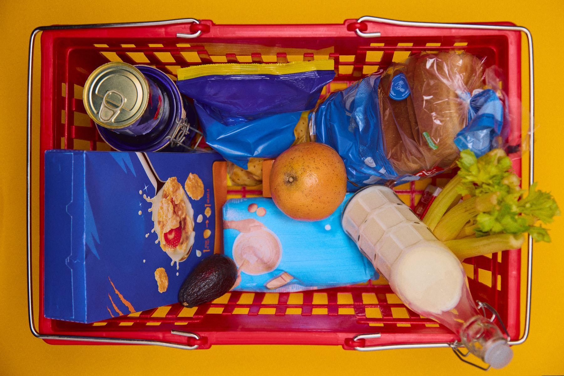 A yellow shopping basket full of groceries seen from above