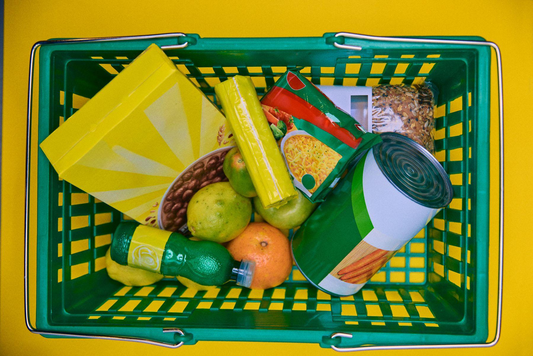 A green shopping basket full of groceries seen from above