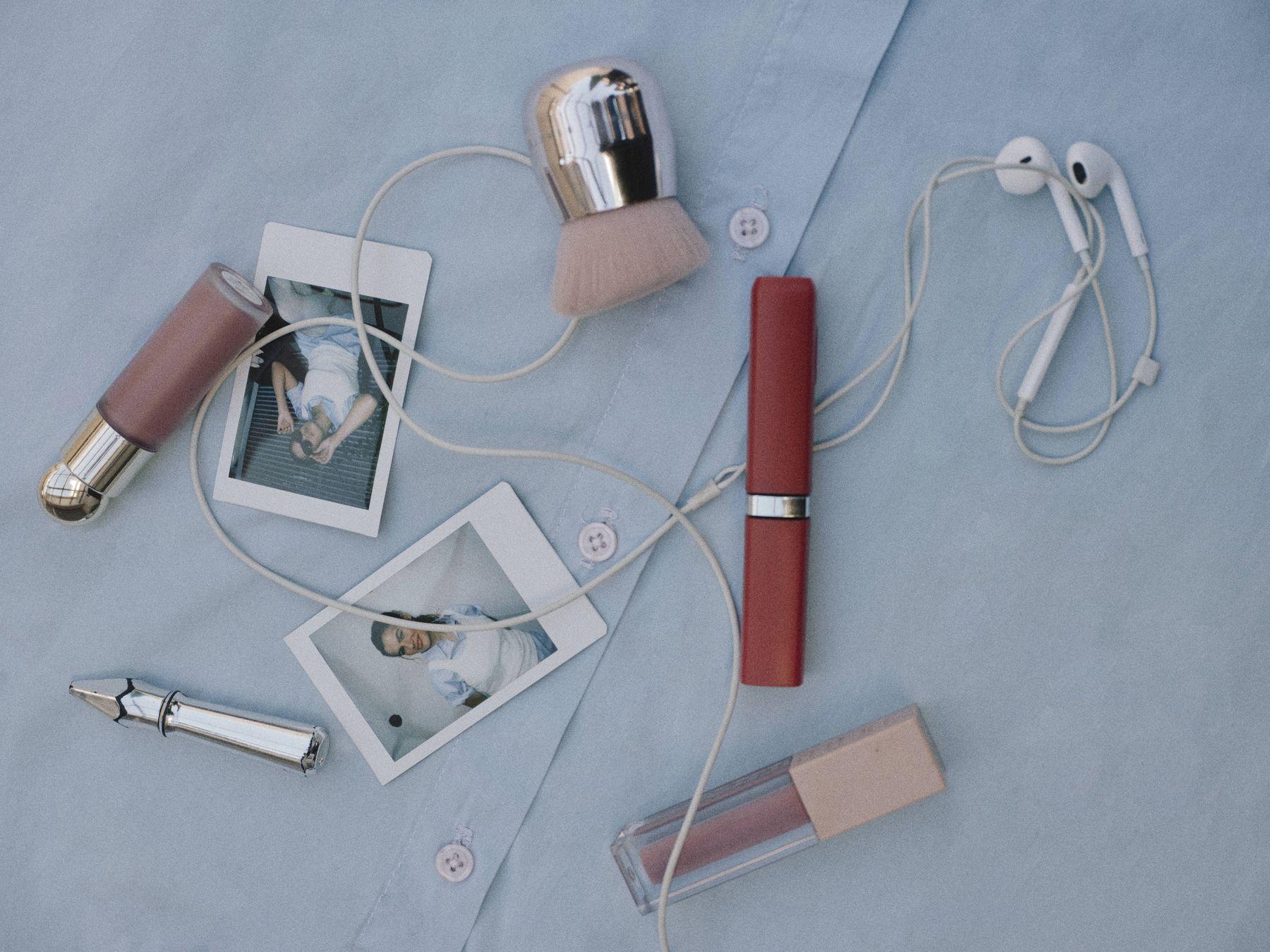 Lipsticks, perfume and photos laid out on blue