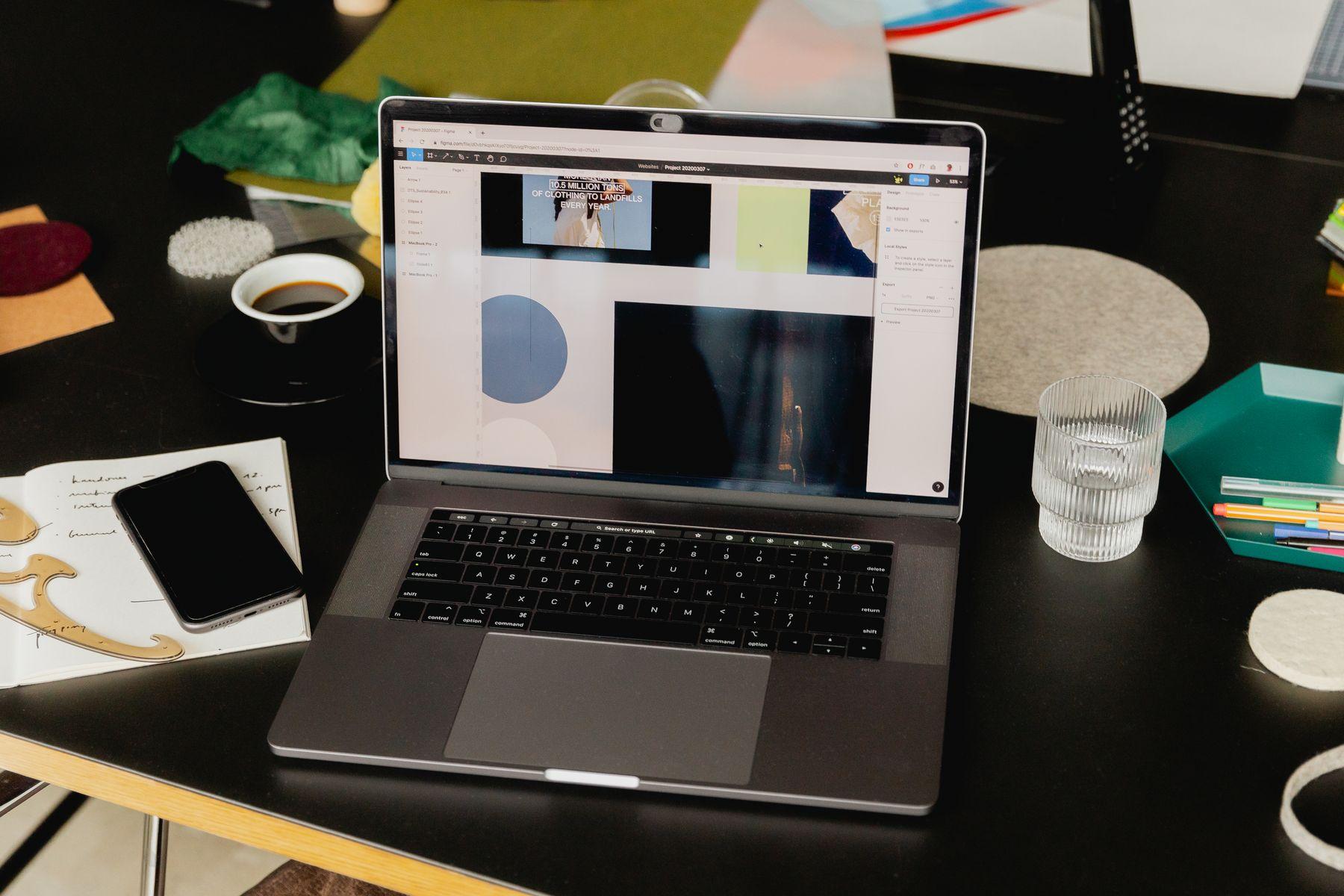 A laptop showing a page design on a desk with swatches