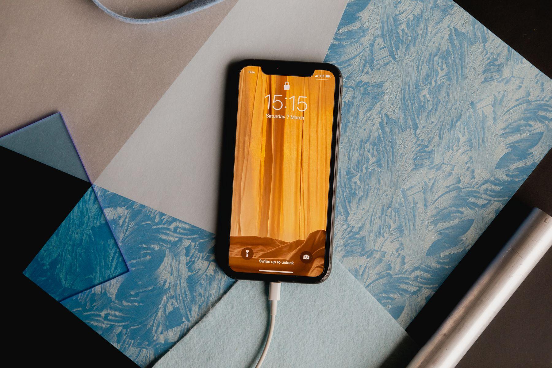 A phone on a green surface beside a charging cable