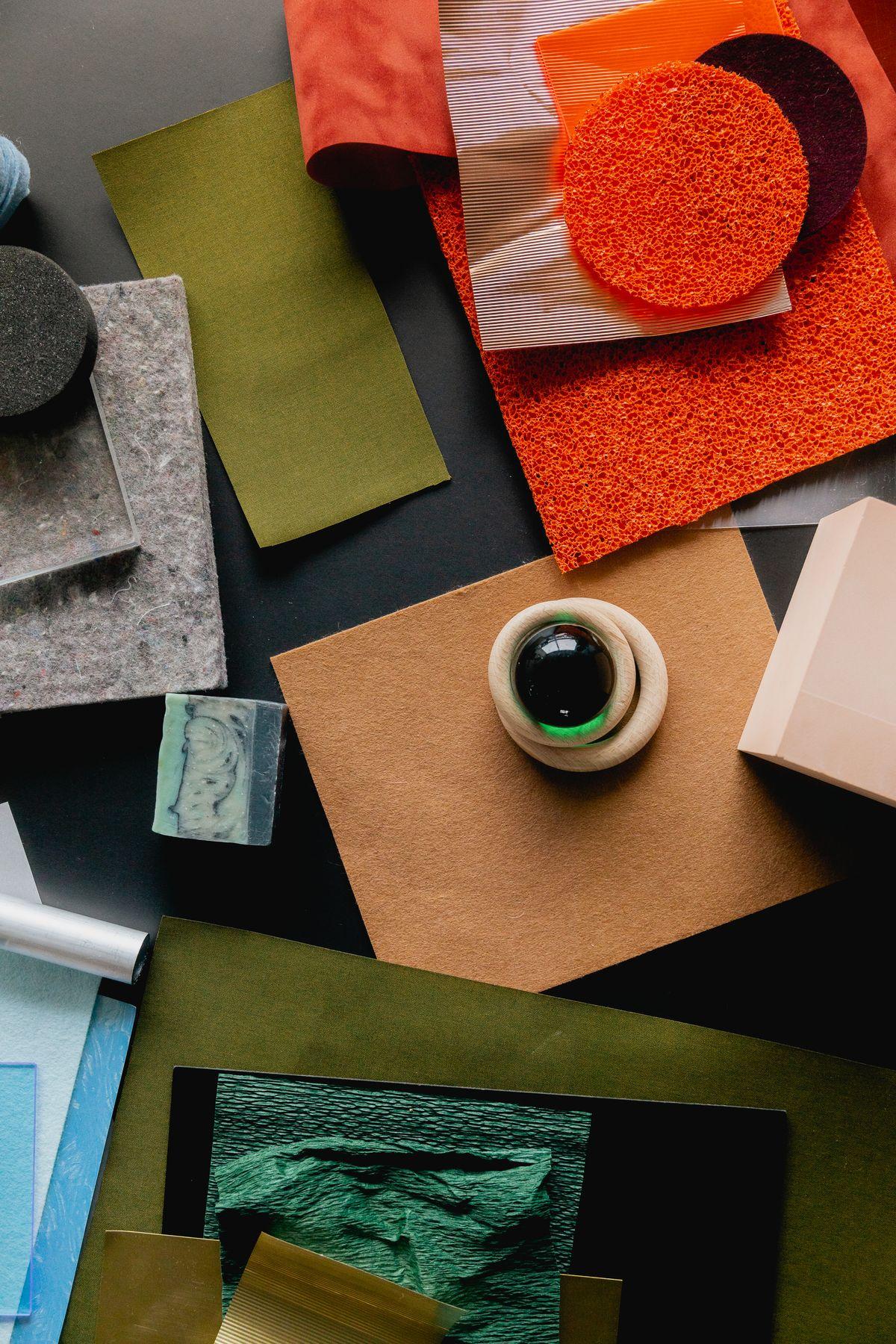 A flat lay of material samples, a ring and colored paper