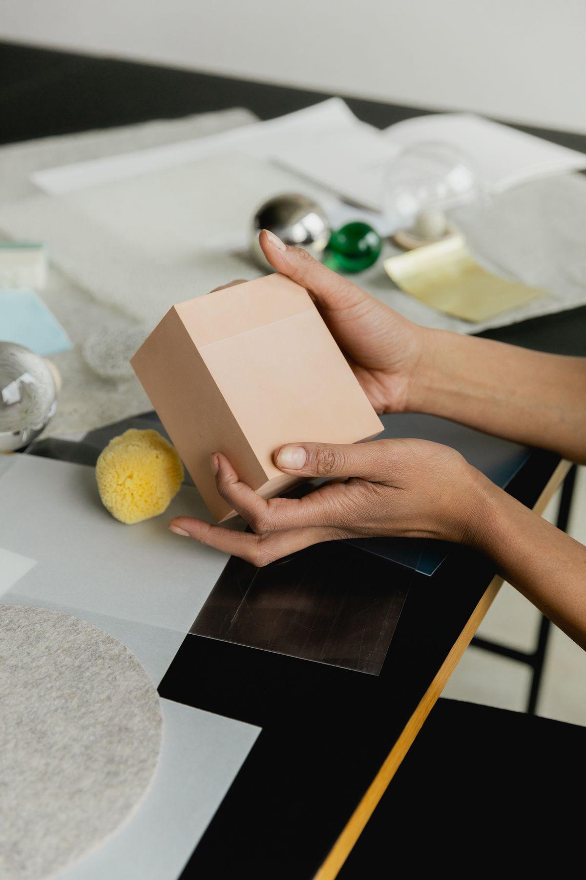Hands holding a small pink box over a table