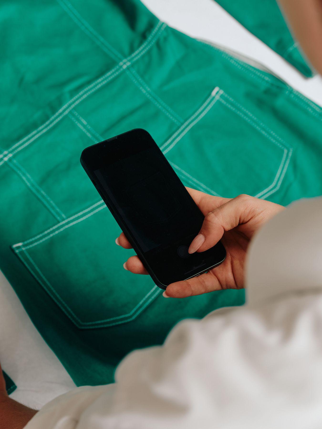 A hand holding a phone over green fabric