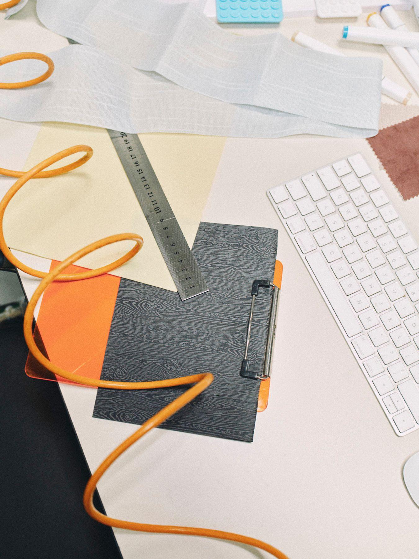 A keyboard, cables and a clipboard on a white desk