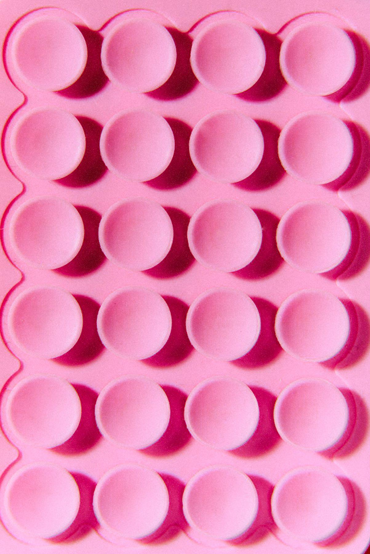 A pink tray of round cups in neat rows
