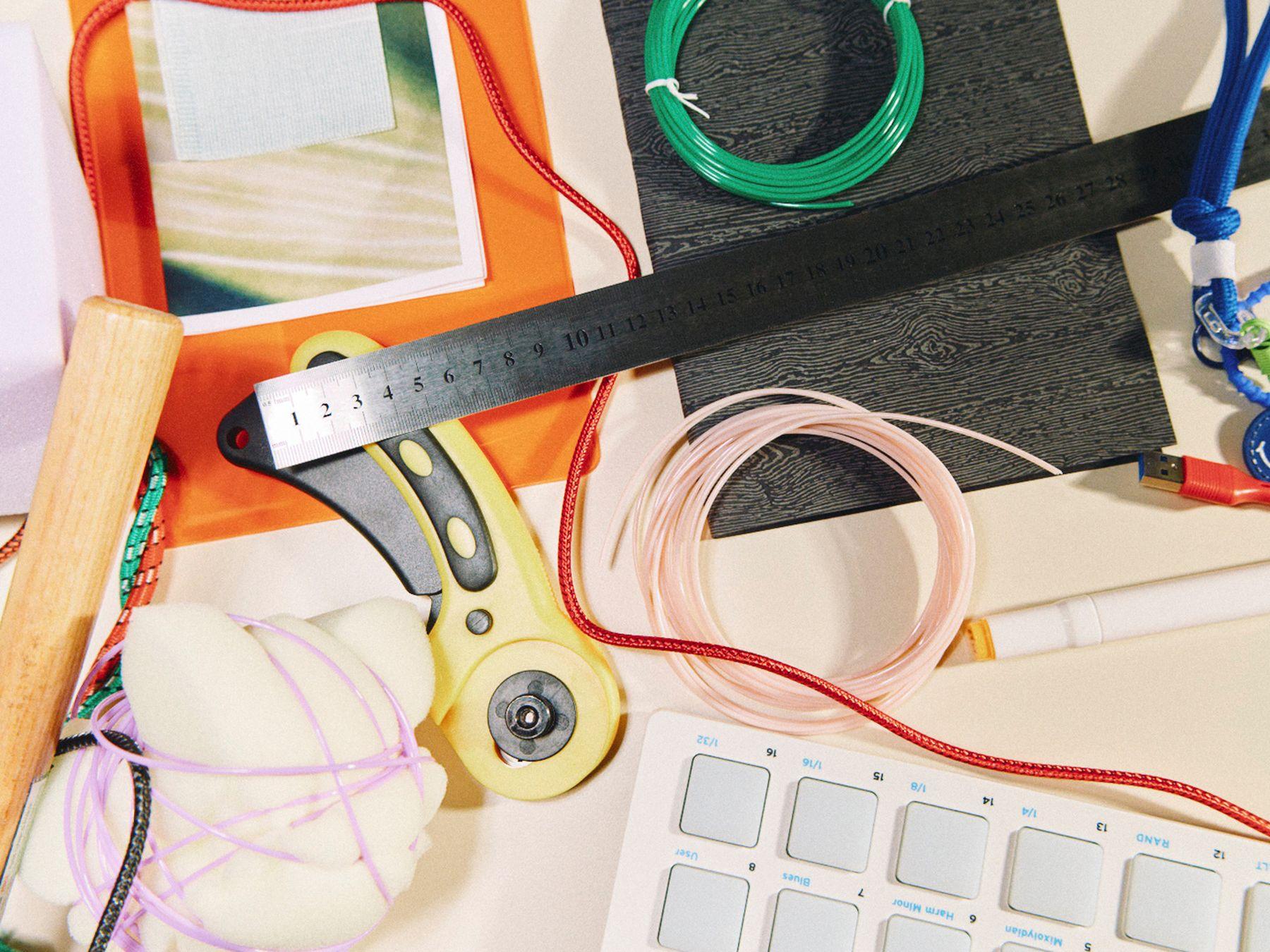 A metal ruler, a cutter and tools on a busy desk