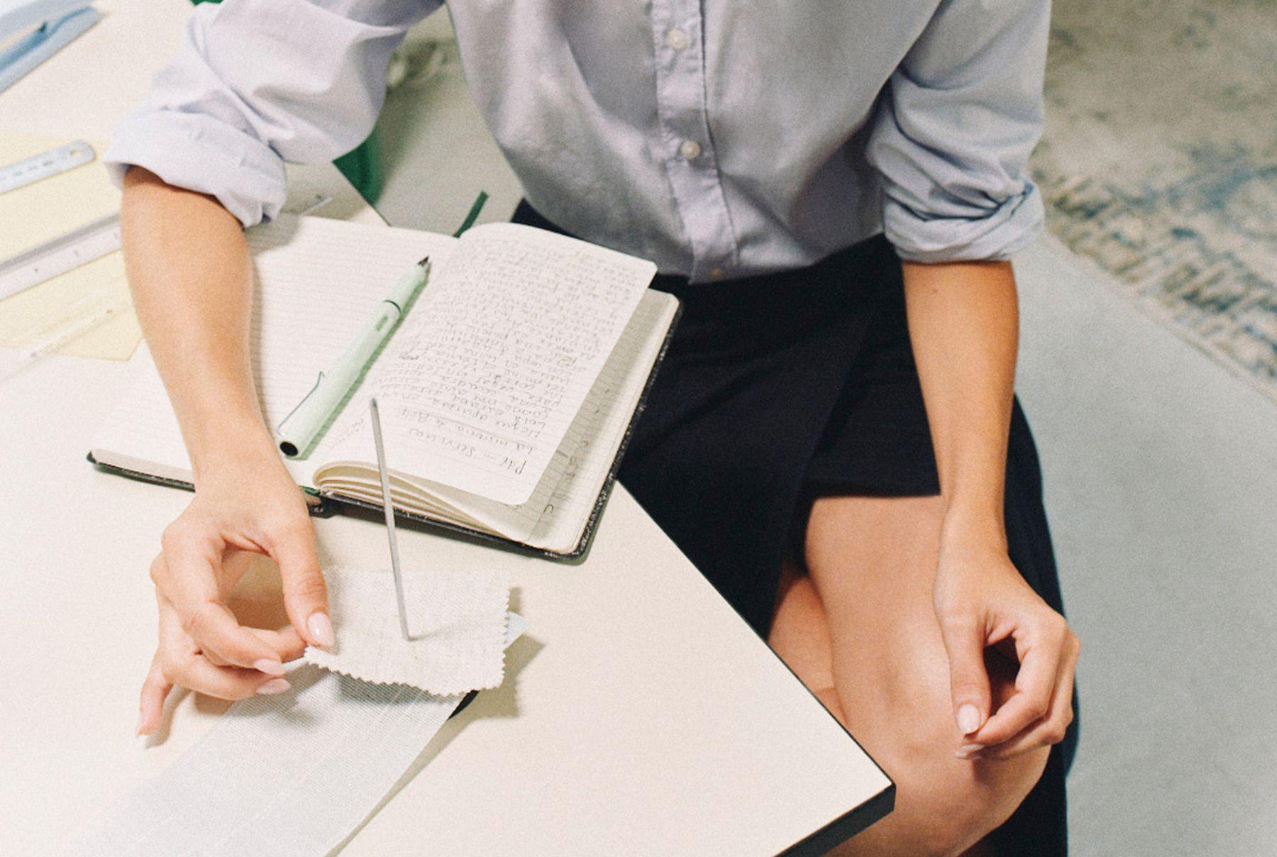Hands holding a pen over an open notebook