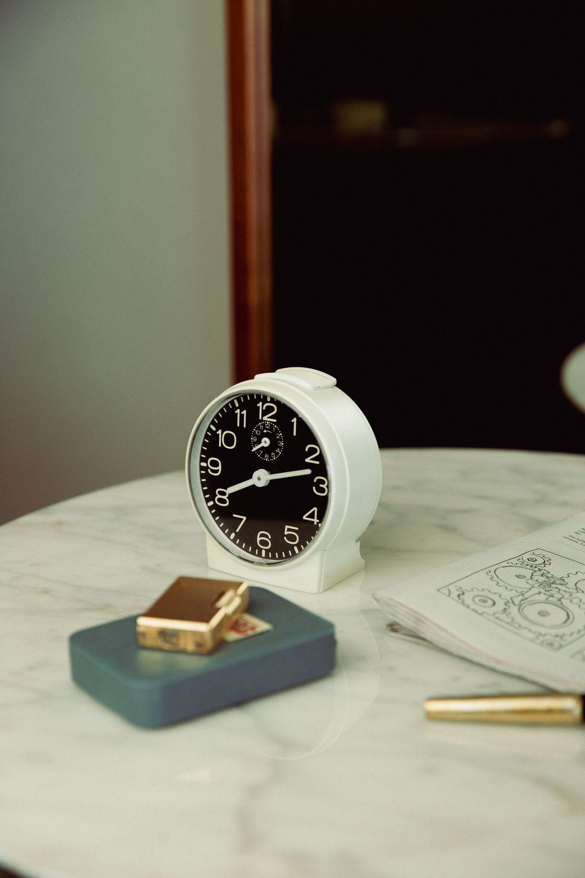 An alarm clock and a small box on a marble table