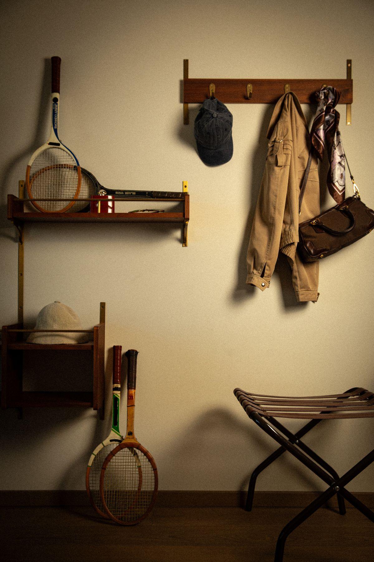 A wall rack with a racket, a jacket and a bag