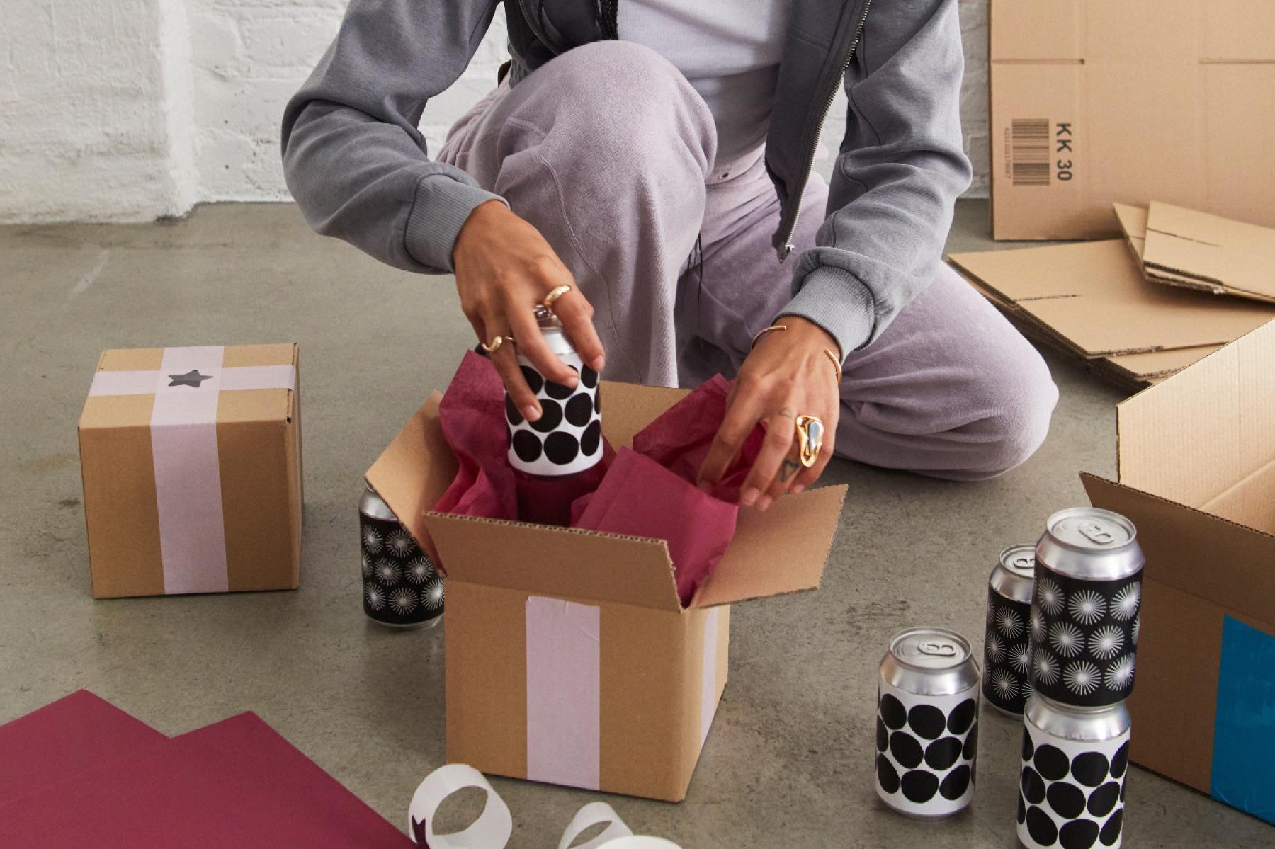 Someone packing orders into boxes with tissue paper on a studio floor