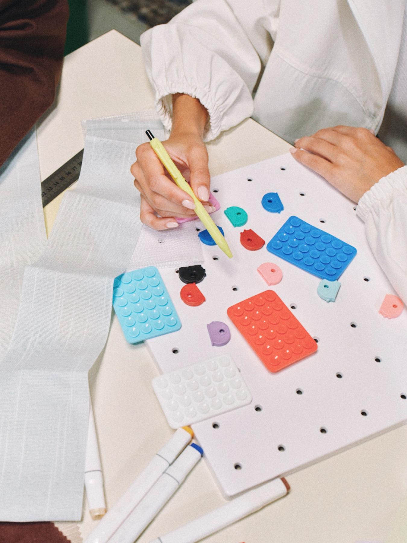 Hands arranging colored shapes and swatches on a pegboard