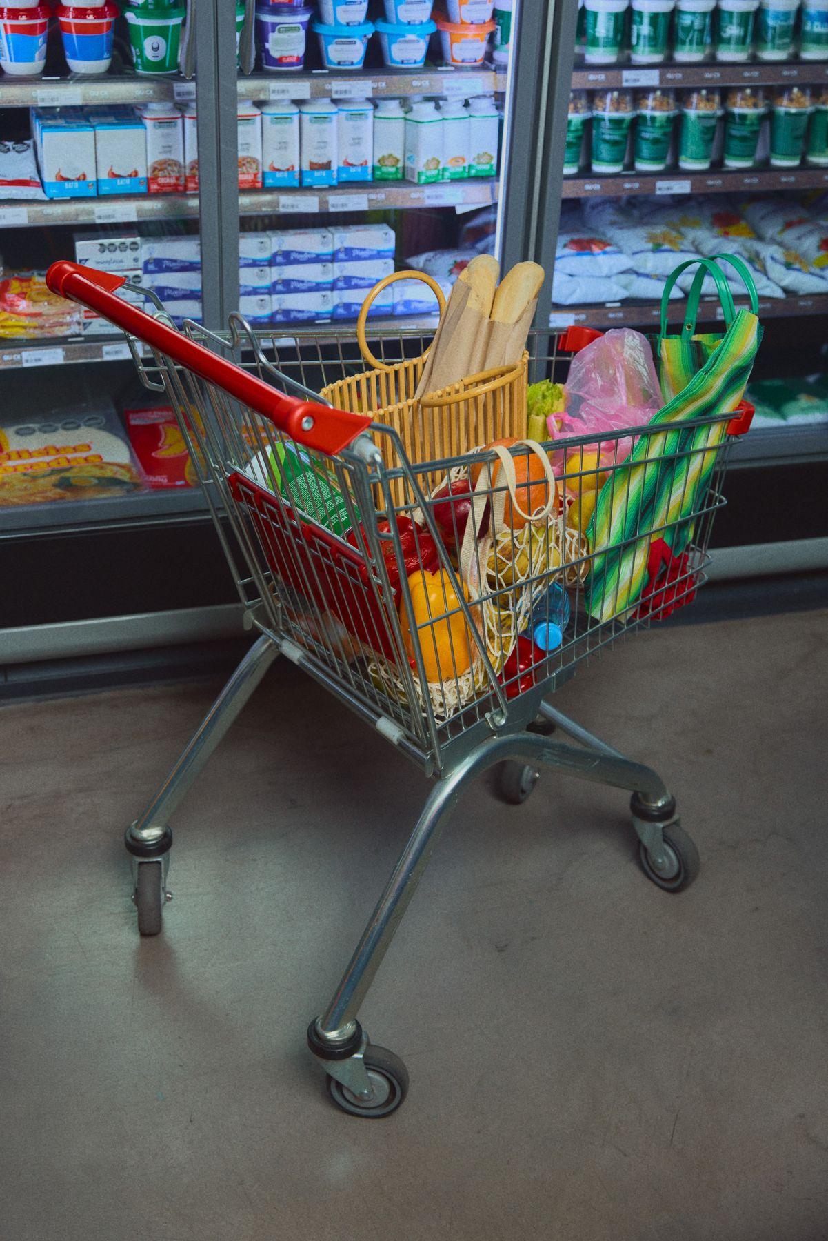 A loaded shopping cart standing in a grocery aisle