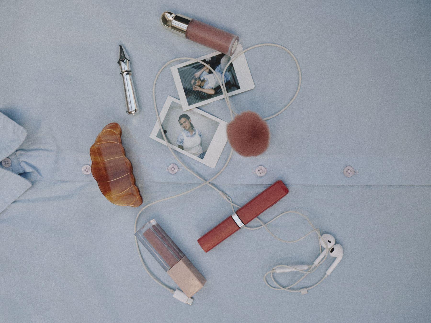 Beauty products and instant photos scattered on blue