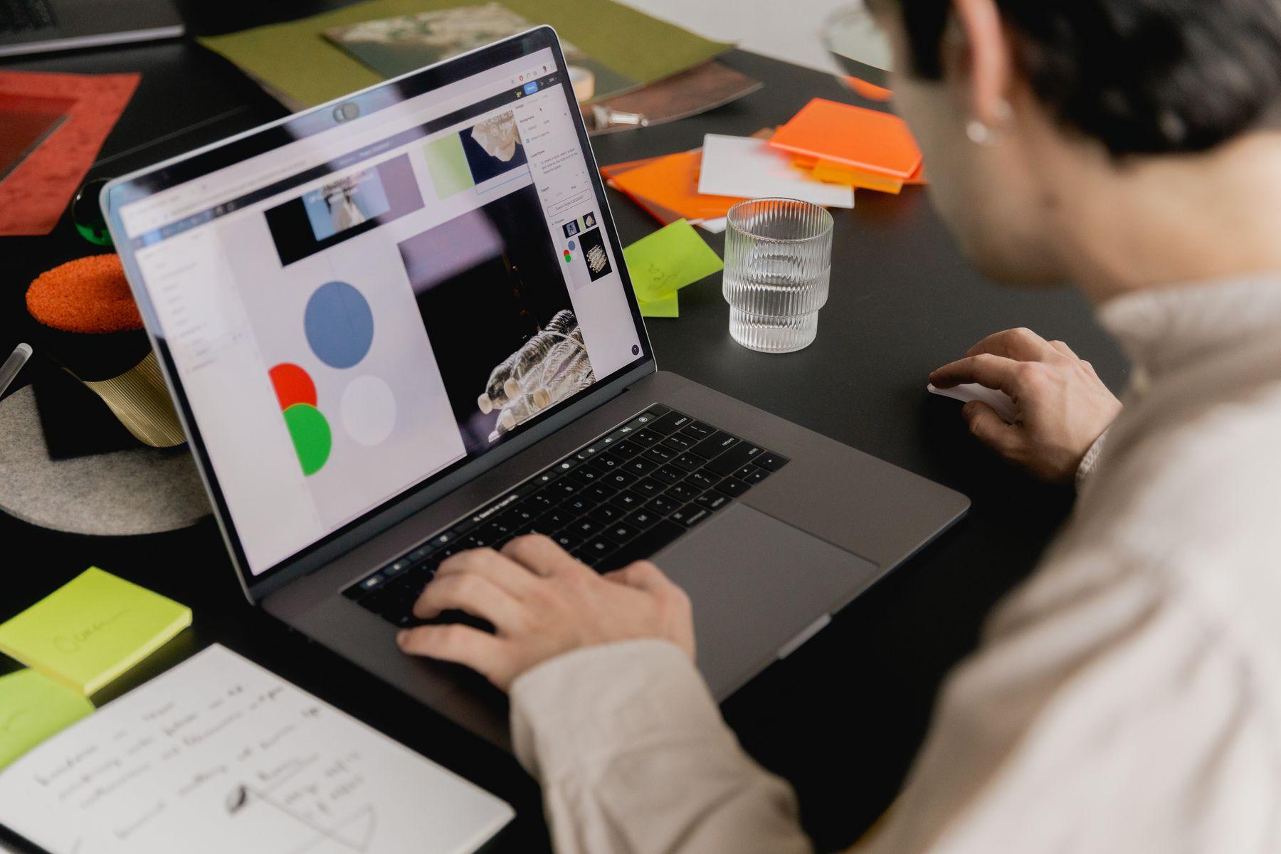 A hand on a laptop showing a web page, with notes nearby