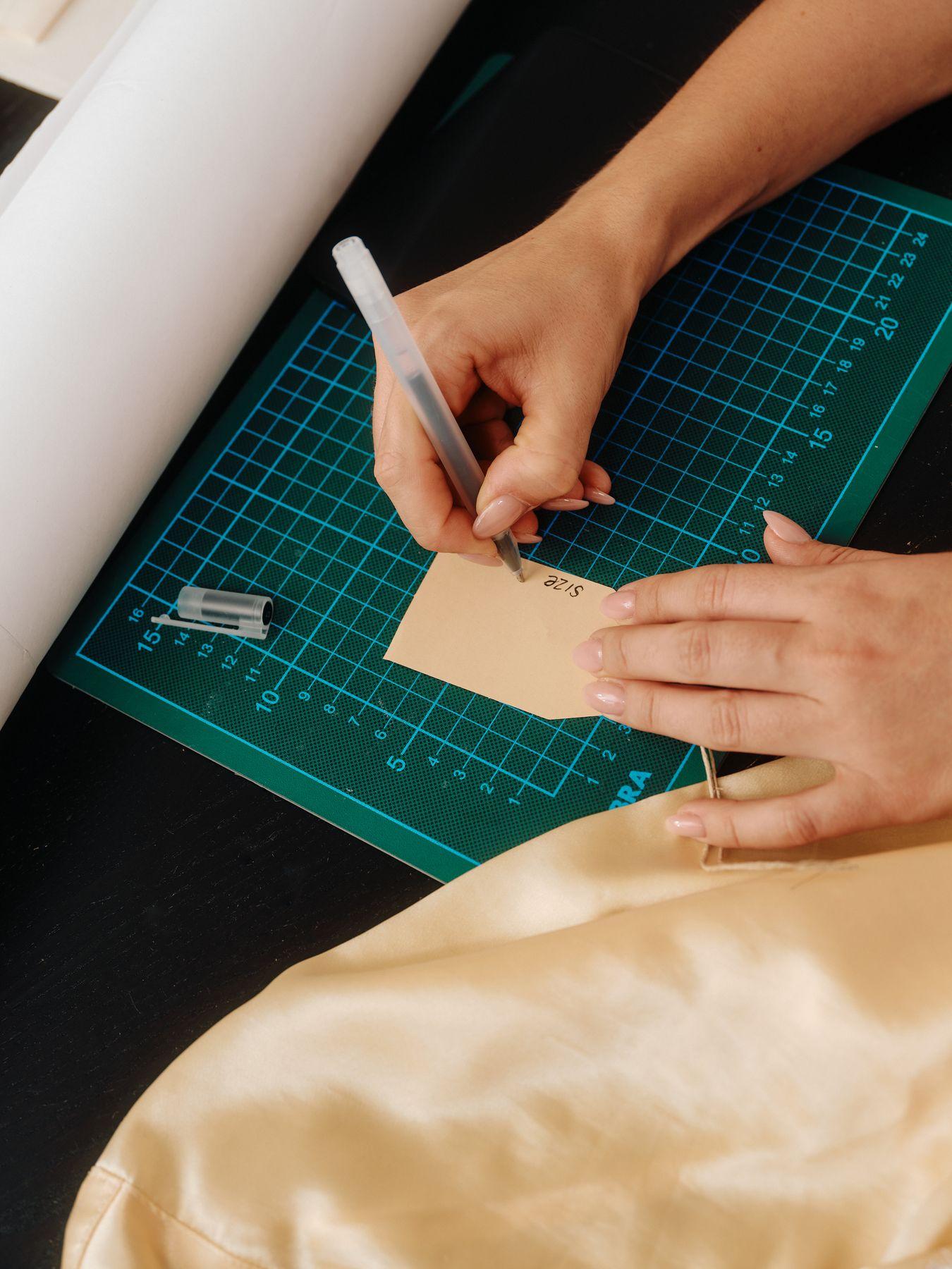 Hands cutting a paper pattern on a green cutting mat