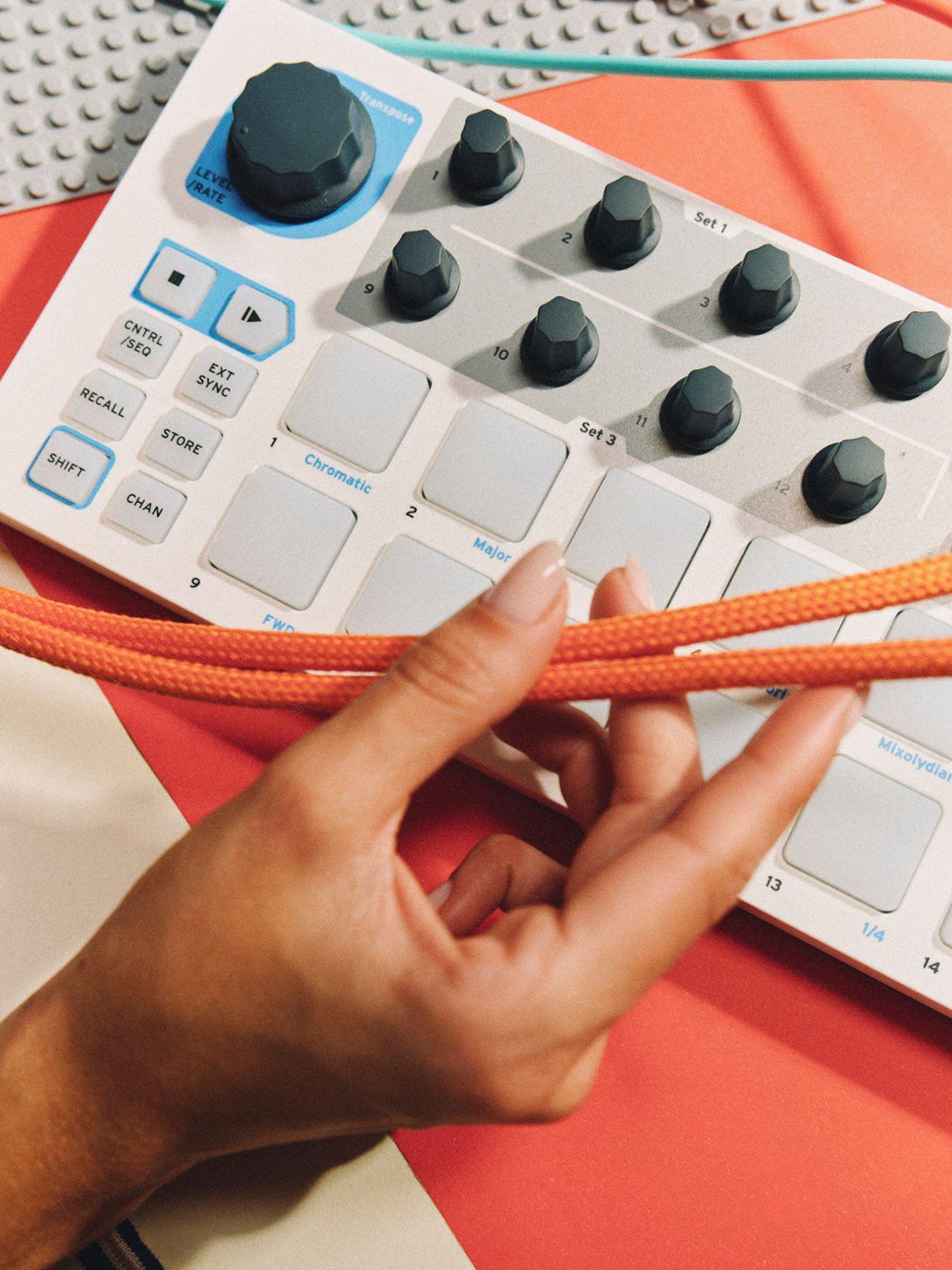 Hands holding cables over a controller with buttons and dials